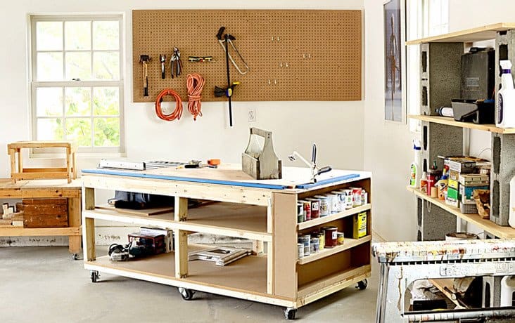 DIY mobile workbench in garage completed with custom shelves, peg board for tools and more.