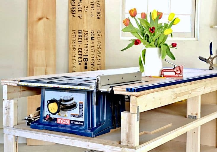 DIY mobile workbench with table saw and a a vase of tulips in garage.