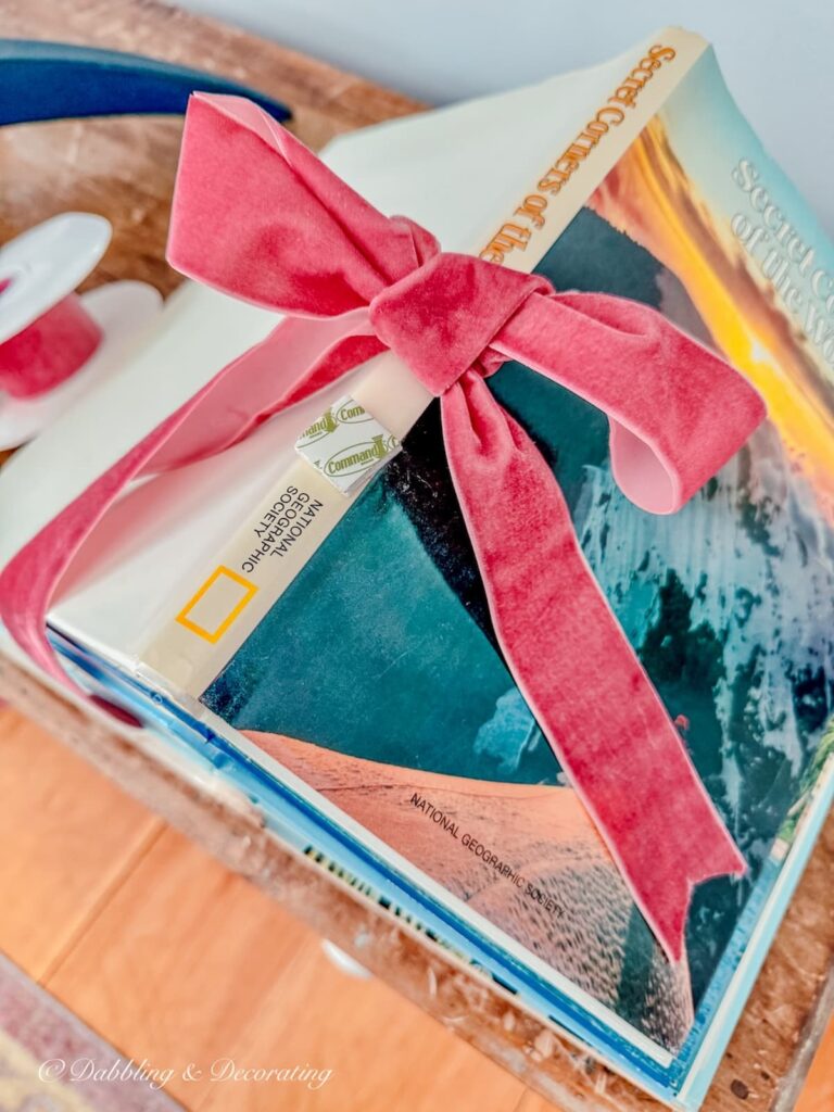 Stack of books with a pink bow and a small piece of velcro to make a book Christmas tree.