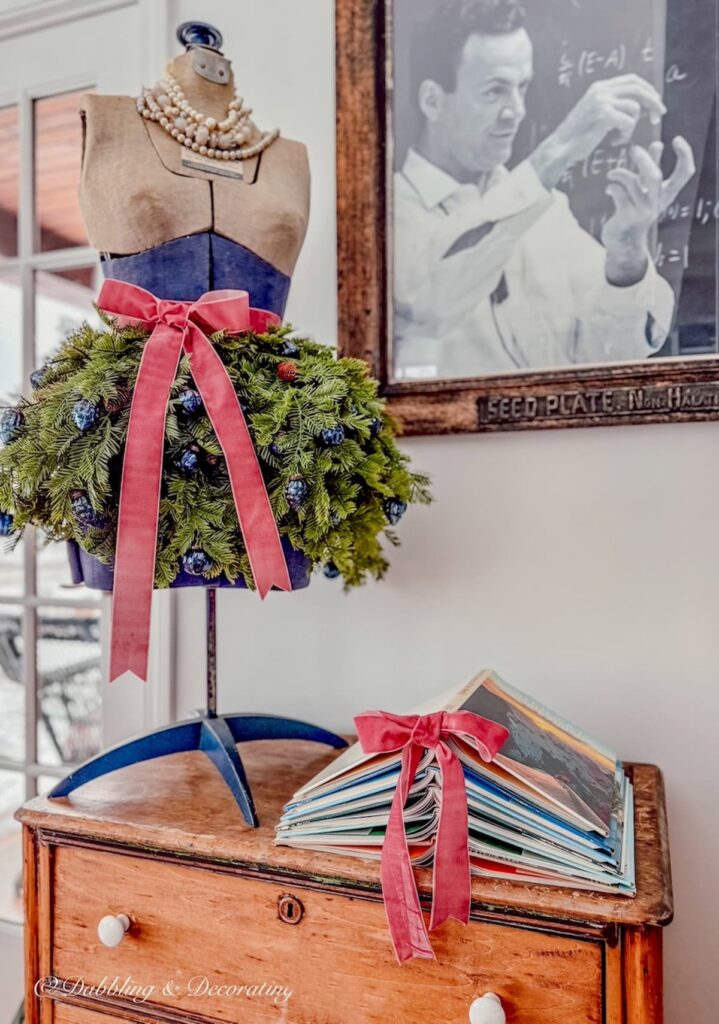 Vintage Christmas mannequin and Book Christmas tree DIY on vintage dresser in sunroom with pink bows.