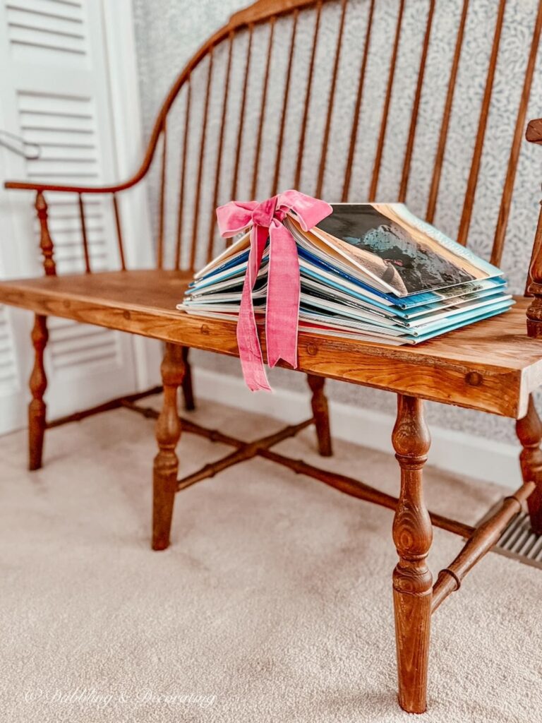 Book Christmas Tree DIY with pink ribbon on a vintage wooden bench in a guest bedroom for the holidays.