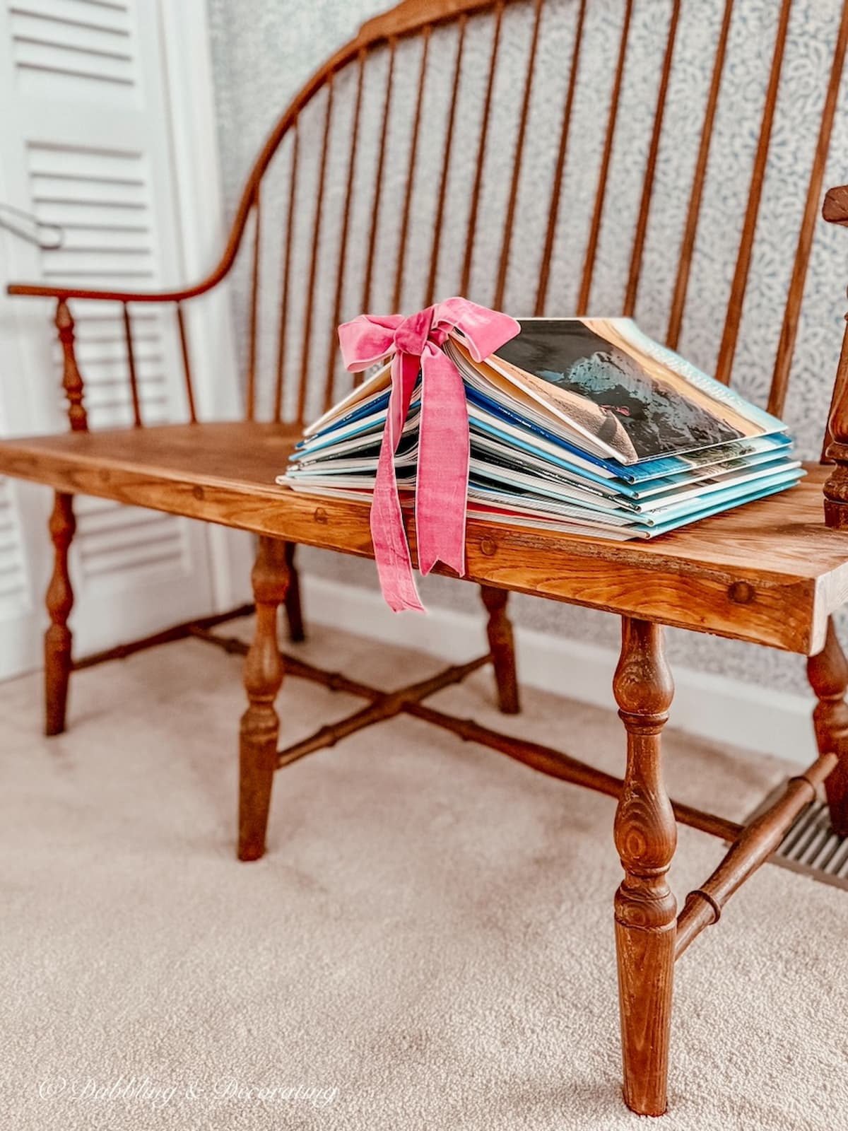 Christmas Book Tree of Knowledge Book Christmas Tree DIY with pink ribbon on a vintage wooden bench in a guest bedroom for the holidays.