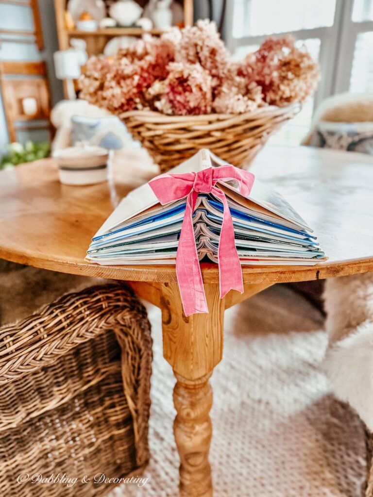 Vintage dining room round pine table with a book Christmas tree with six books and a pink ribbon for a holiday accent.