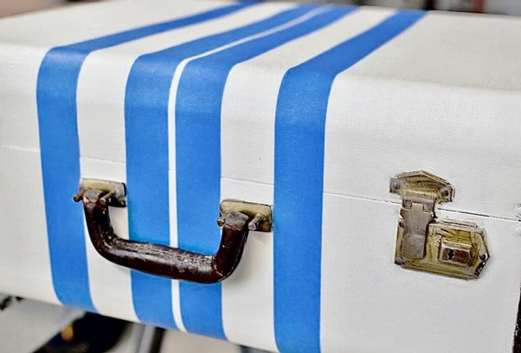 Luggage painted white with blue painters tape as striping.