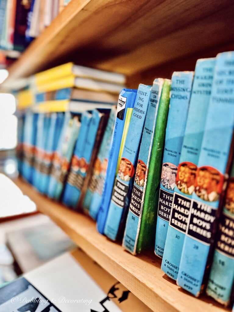 Vintage blue Hardy Boys books sit on a bookself