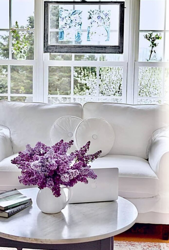 Vintage Room decorated with lilacs, white love seat and salvaged window.