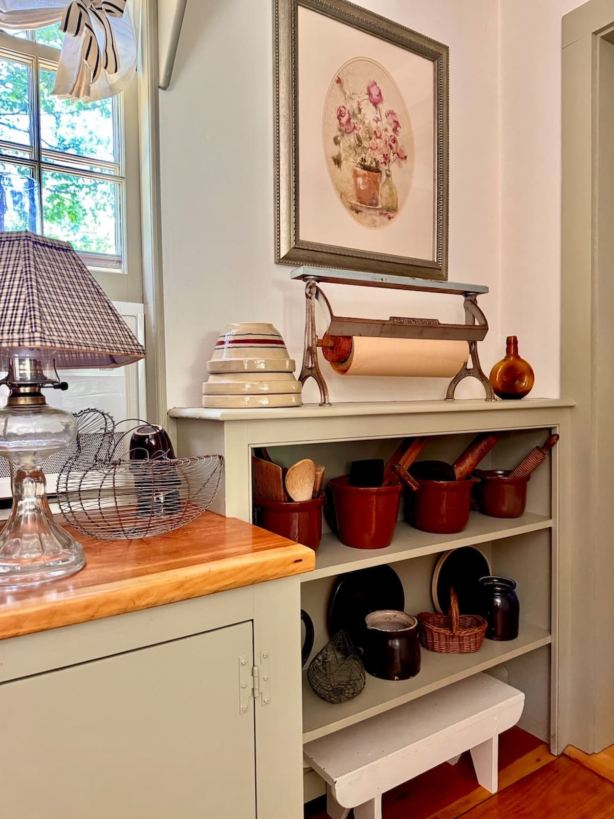 Vintage paper cutter in primitive style kitchen displayed on built in shelving.