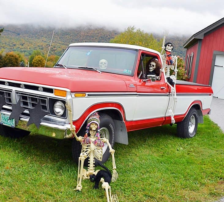 Vintage Ford Truck full of Halloween Skeletons Vintage red and white truck decorated with Halloween skeletons in hats, wigs, and more in the fog.