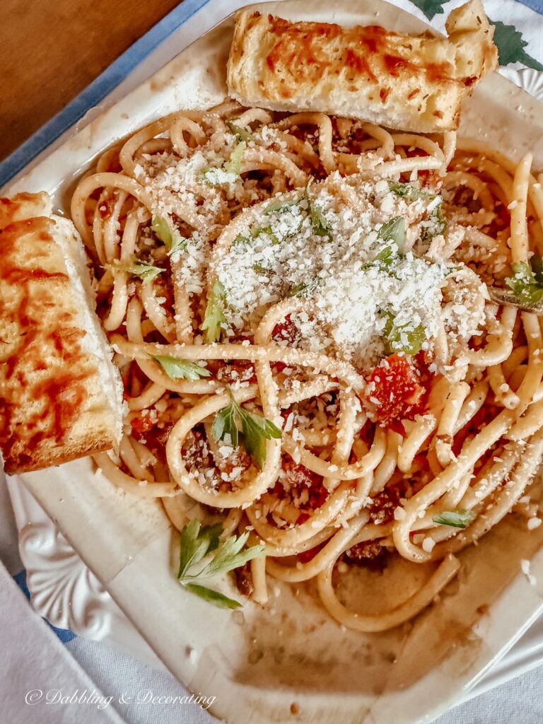 Pasta Bolognese with parsley, parmesan cheese and garlic bread in a bowl.