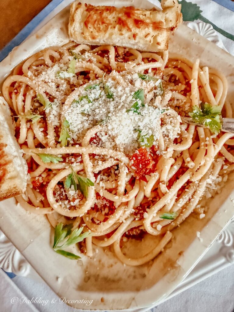 Pasta bolognese in bowl with parmesan cheese, parsley and garlic bread in Italian bowl.