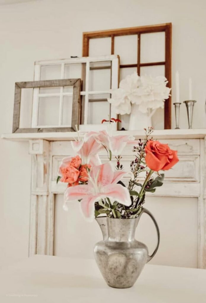 Vintage flower arrangement in front of vintage white mantel with old windows layered.