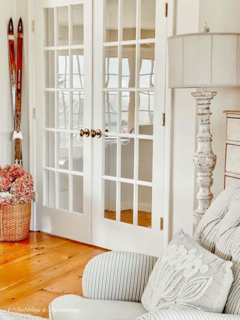 French doors in sitting area of home with Navajo White Sherwin Williams on the wall styled with neutral decor.
