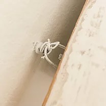 Vintage faux mantel install with screw attached to the wall with wired piece attached to mantel close up.