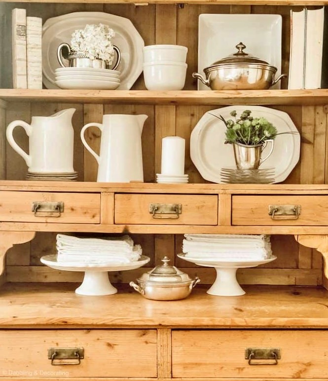 Vintage hutch decorated with white and silver, farmhouse style.