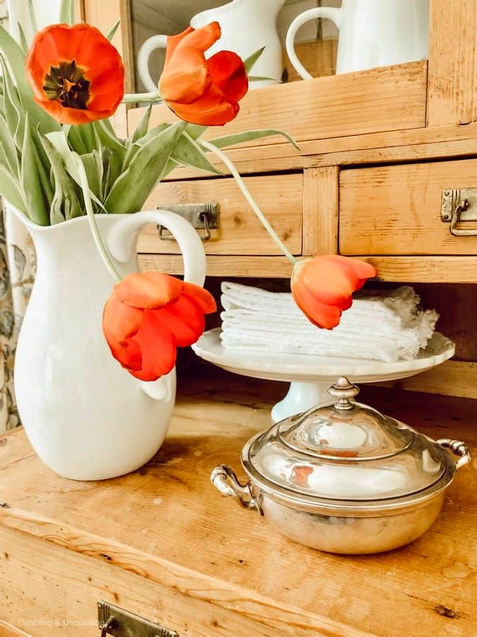 Orange tulips on vintage farmhouse cabinet.
