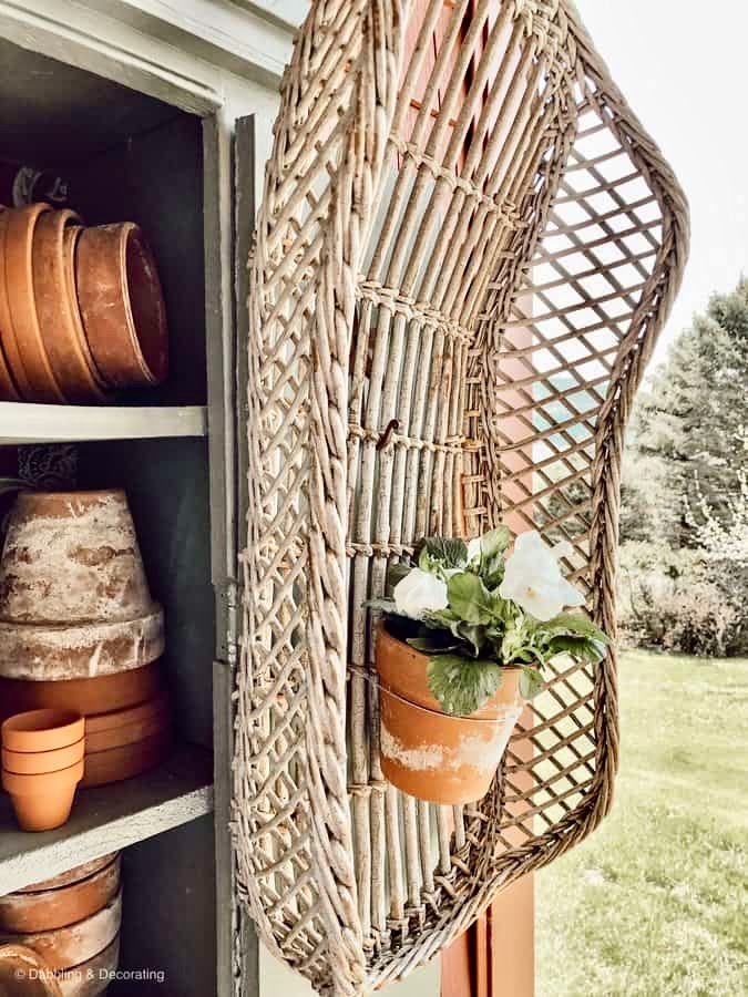 Garden cupboard with terracotta pots and large basket on door.
