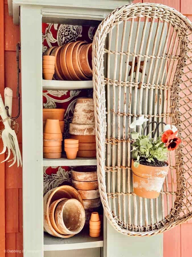 Garden cupboard with terracotta pots and pansies.