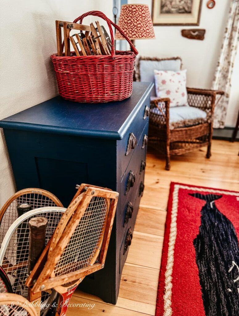 Tennis racket decor ideas with a red basket of wooden presses on blue dresser and wooden tennis rackets in bedroom's basket on floor.