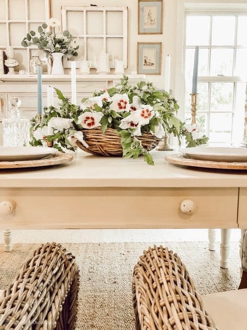 Rose of Sharon Farmhouse Centerpiece in flat basket on white farmhouse table in vintage styled dining room.