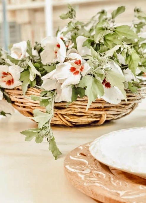 Basket centerpiece with Rose of Sharon flowers on farmhouse table.