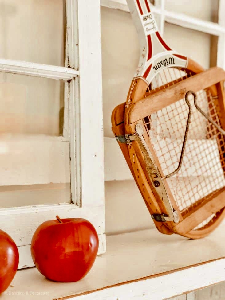 Vintage Tennis racket with red apple on Mantel