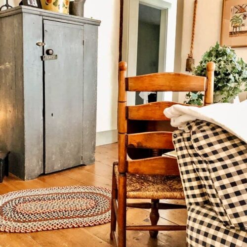Antique dining chair with braided rug, antique blue hutch, corner of the this signature coastal home before renovations.