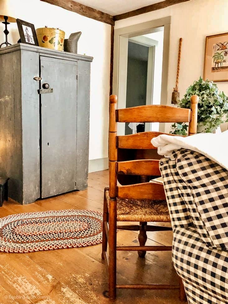 Antique dining chair with braided rug, antique blue hutch, corner of the this signature coastal home before renovations.