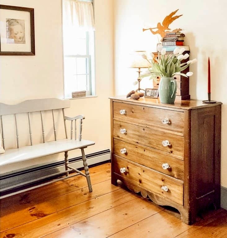 Master bedroom antique dresser with blue bench, wood flooring in Raeside-Dame home before.