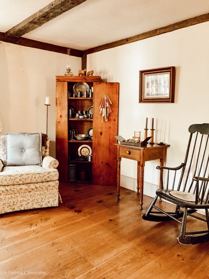Inside Raeside-Home before living room corner with antique hutch and furnishings with pewter collection and wood floors.