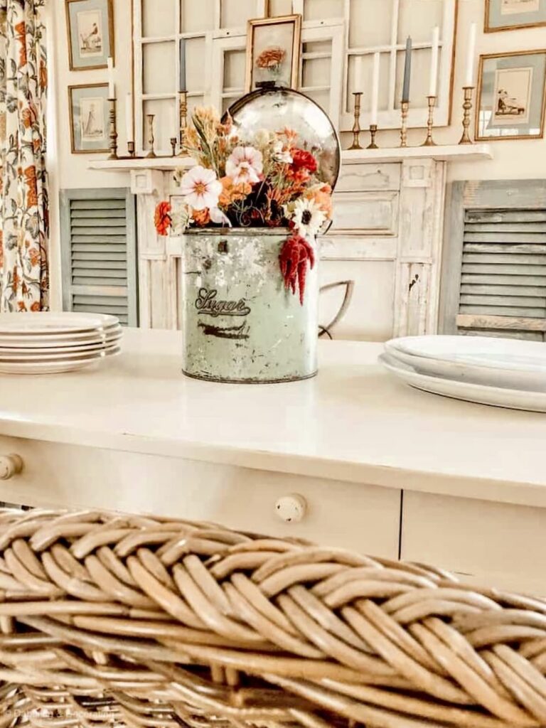 Vintage green sugar tin with flowers on a white farmhouse table as a seasonal centerpiece.