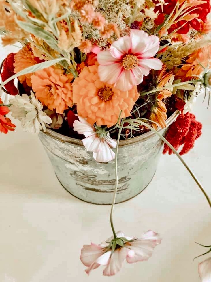 Flowers in a tin for a vintage inspired centerpiece on white farmhouse style table.