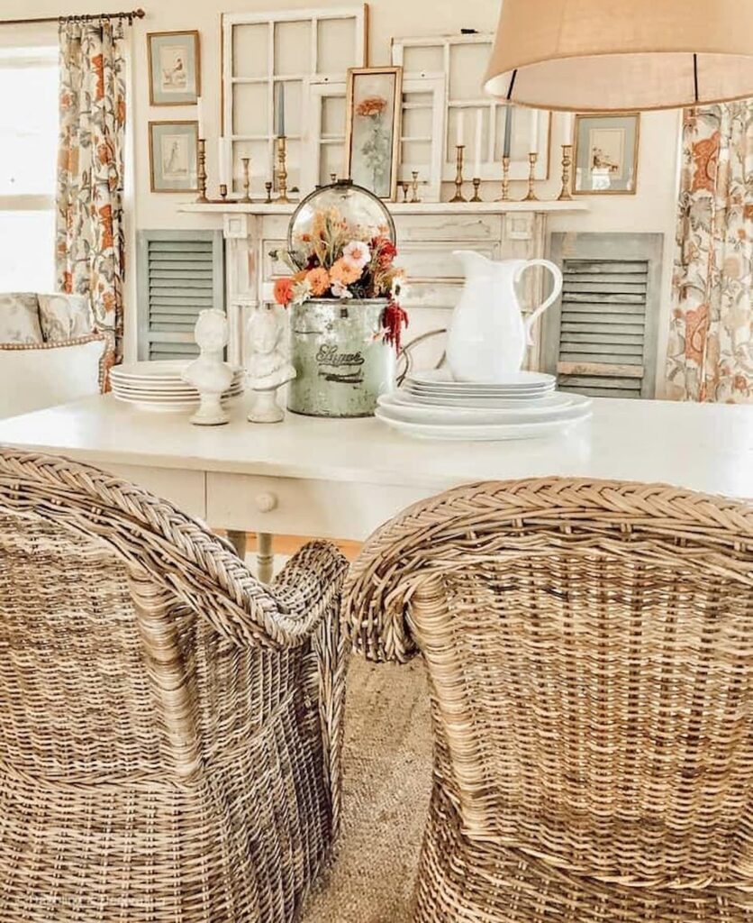 Vintage Farmhouse styled white dining room with white farmhouse table and seasonal tin decor centerpiece and wicker chairs.