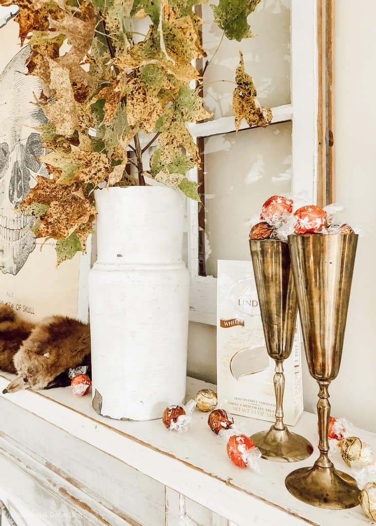 Halloween Vintage Mantel ideaswith Lindt Lindor Chocolate filling two brass champagne flutes, an architectural salvage piece filled with fall branches and a thrifted mink.