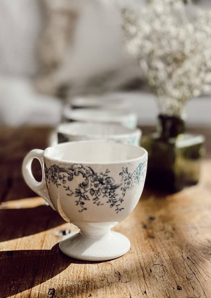 Antique finds, white and blue teacups on pine table.
