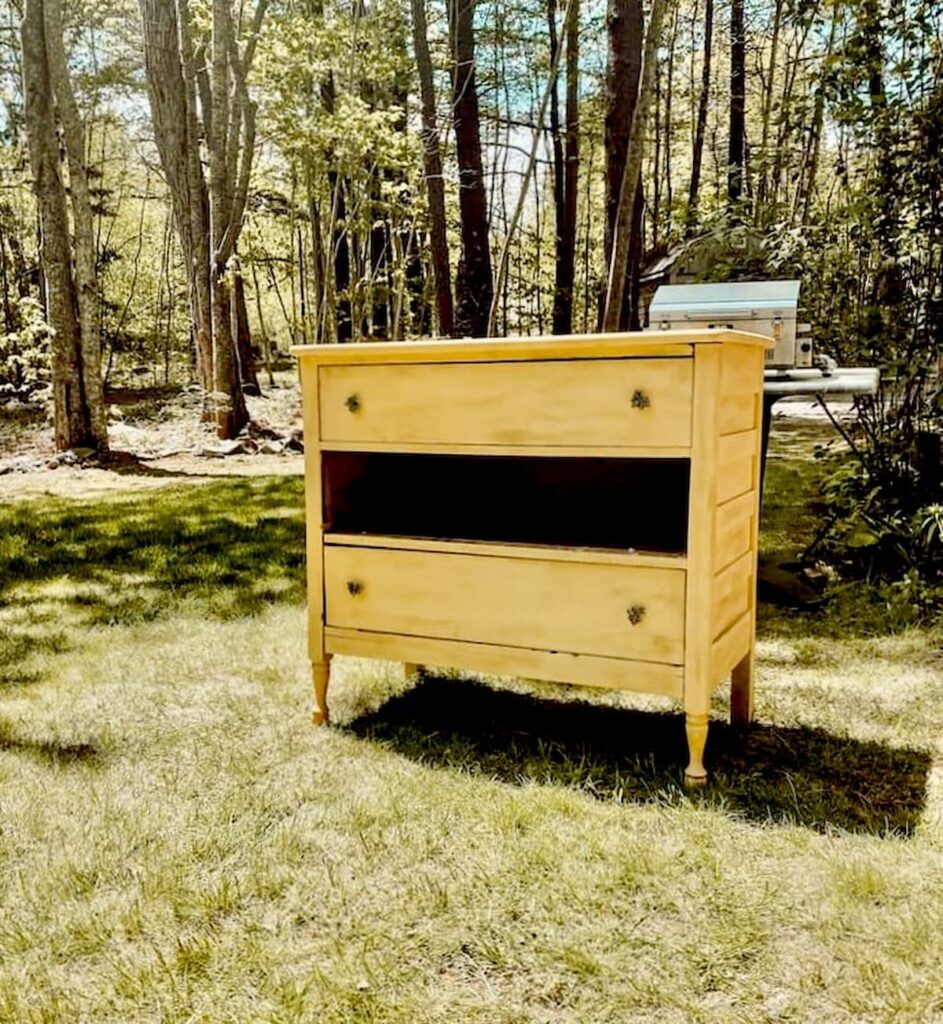 Old yellow dresser with a missing drawer in yard to create DIY grill station with.