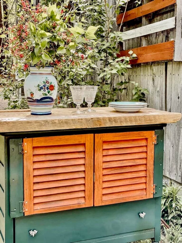 DIY grill station with orange shutters and old green dresser with barn wood top.
