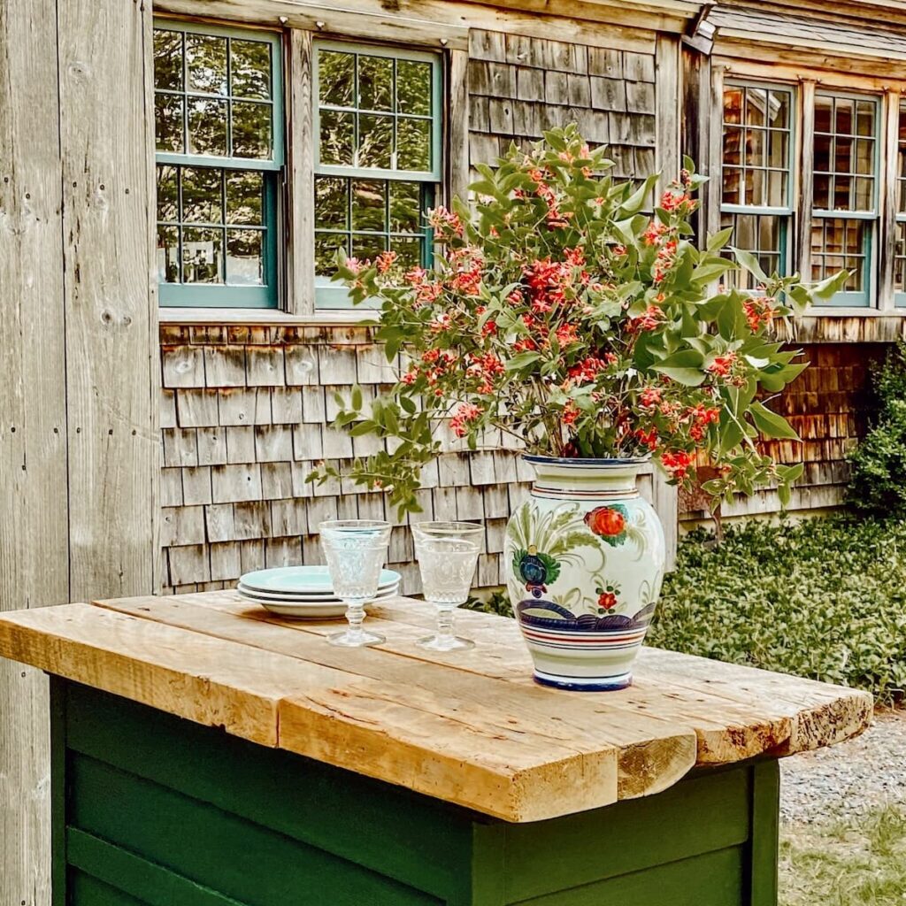 DIY grill station with barn wood top on old green dresser with summer bouquet in backyard.