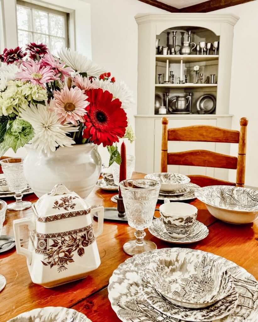 Brown Transferware on dining room table with bouquet of flowers.