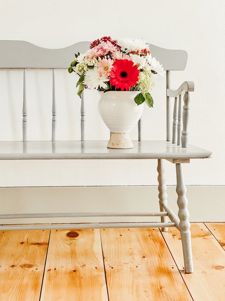 Bouquet of flowers on vintage bench on newly renovated pine wood floors in vintage home renovation.
