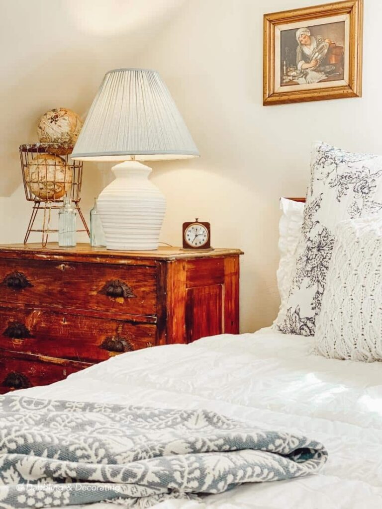 Antique wooden dresser next to bed in small vintage styled bedroom.