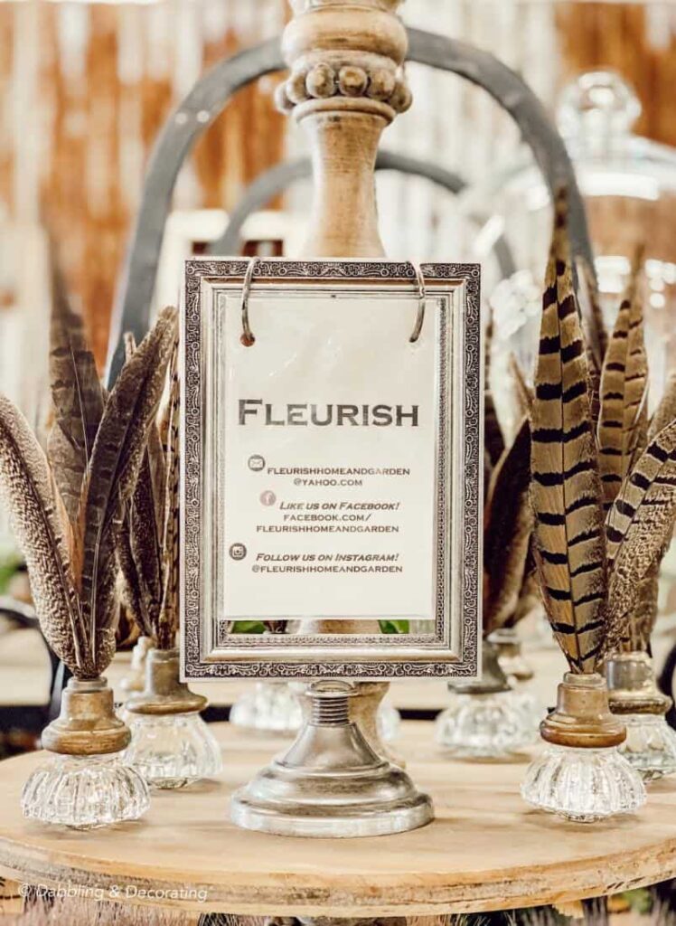 Fleurish Sign between pheasant feathers in glass door knobs at Vintage Market Days Vermont.