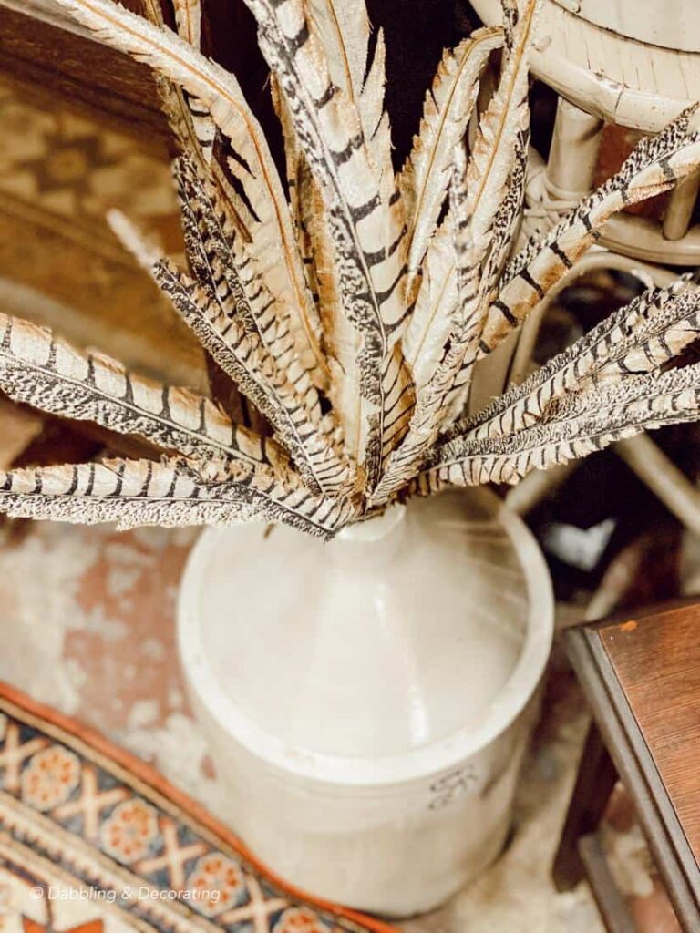 Antique crock with pheasant feathers at antique market.