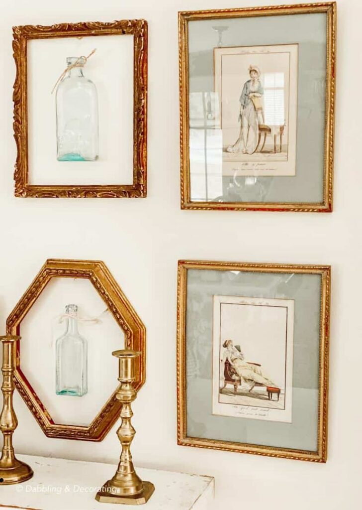 Layering vintage gold frames on wall decor with bottles and brass candlesticks.