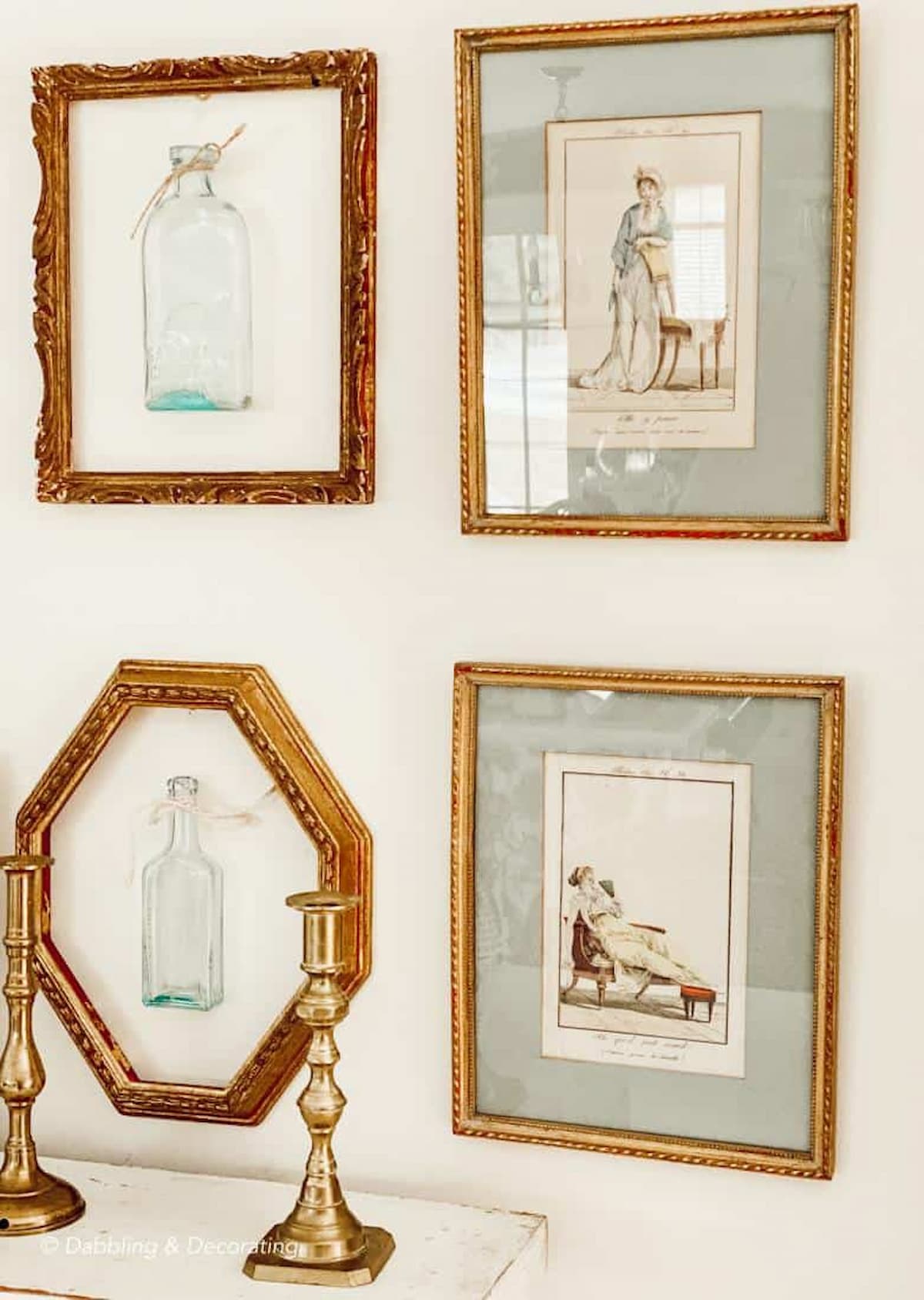 Layering vintage gold frames on wall decor with bottles and brass candlesticks.