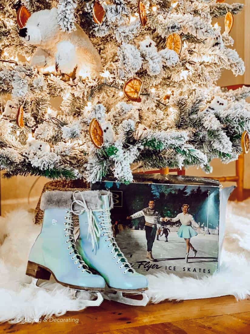 Vintage blue ice skates with box under Christmas tree and on white sheepskin.