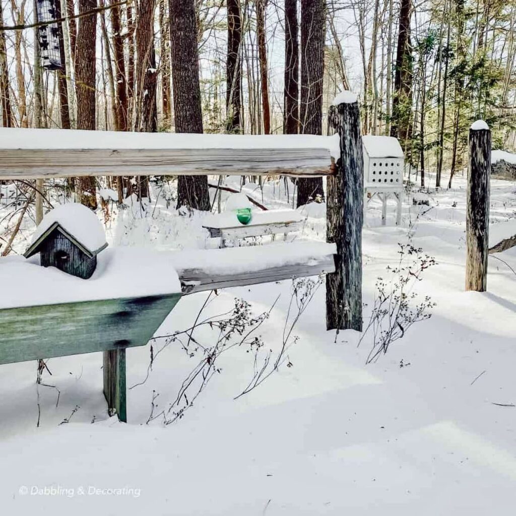Snowy fence with birdhouses, bench and water bobber.