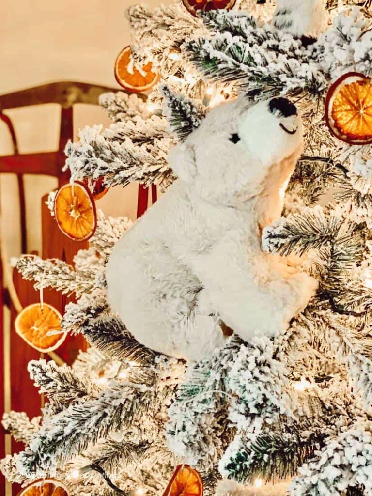 Polar Bear Christmas Decor on King of Christmas flocked tree with dried orange Christmas tree ornaments.