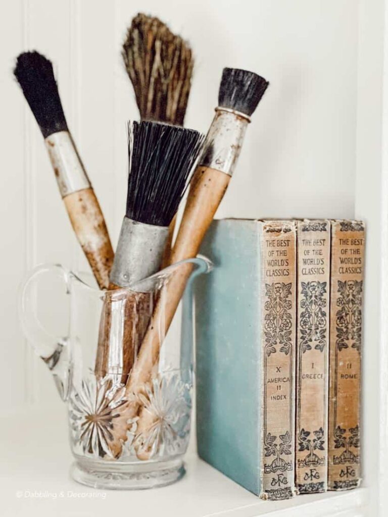 Vintage Bookshelf Decor with old paintbrushes and blue books.