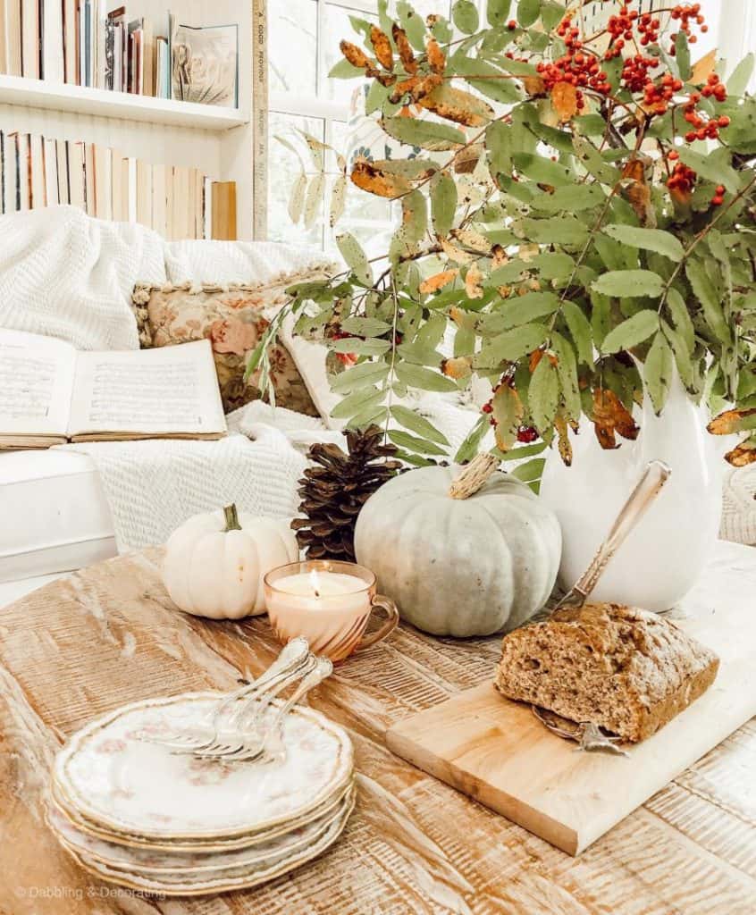 Cozy fall sunroom coffee table styling with banana bread, neutral pumpkins and foraged centerpiece.