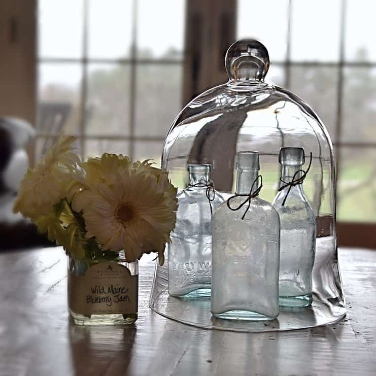 Cloche with blue vintage bottles and yellow flowers.